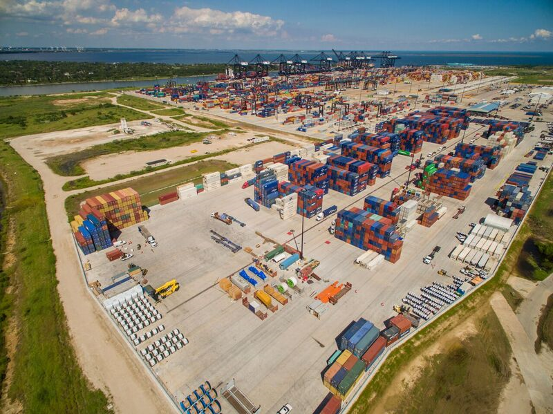 Aerial photo of a commercial shipping yard. Stacks of cargo containers line the space.