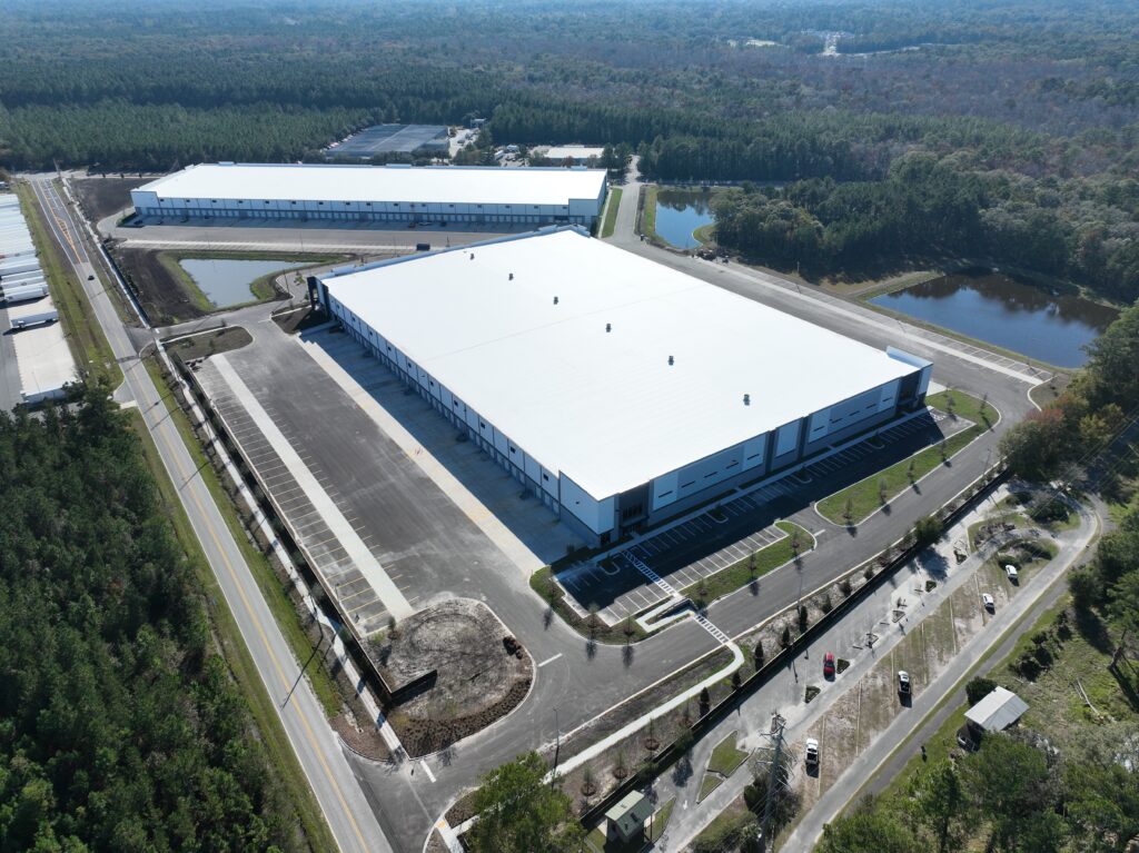 Aerial view of the expansive Inlight Commonwealth Distribution Center, a hub featuring Buildings 200 and Buildings 100, nestled amid roads, parking lots, and lush greenery.