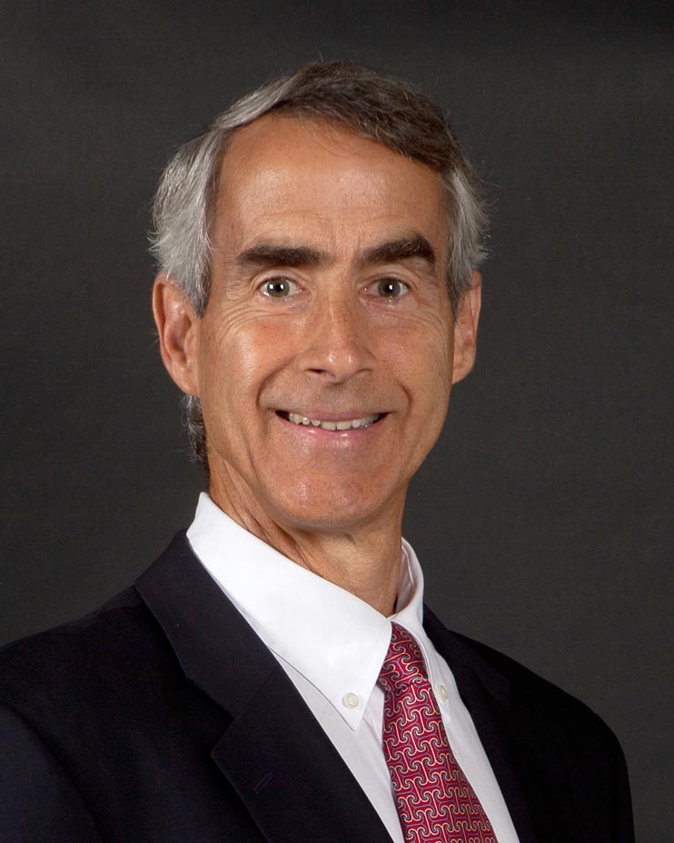 Bob Gillander, Development Officer, poses against a black background in a black jacket, white shirt and red tie