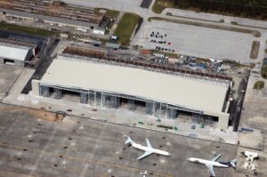 Aerial view of Flightstar’s Hanger 815 under construction, showcasing tenant improvements with two commercial airplanes and a small aircraft parked nearby on the tarmac.