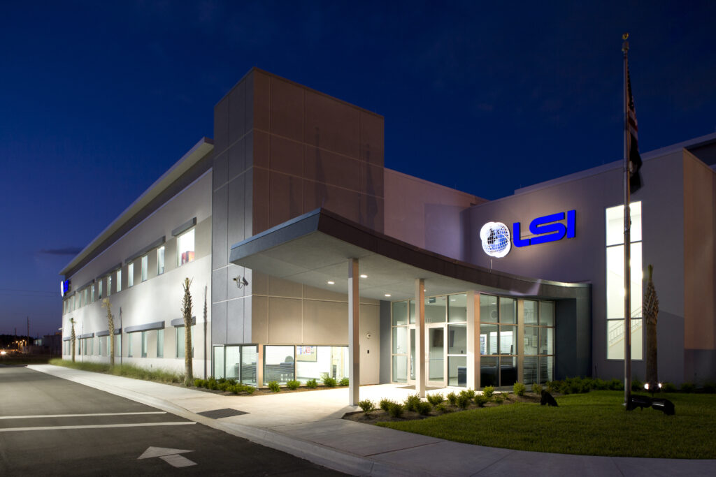 Modern office building with "LSI" logo on the facade, located in Cecil Commerce Center, lit up at night with a glass entrance and landscaped walkway in front.